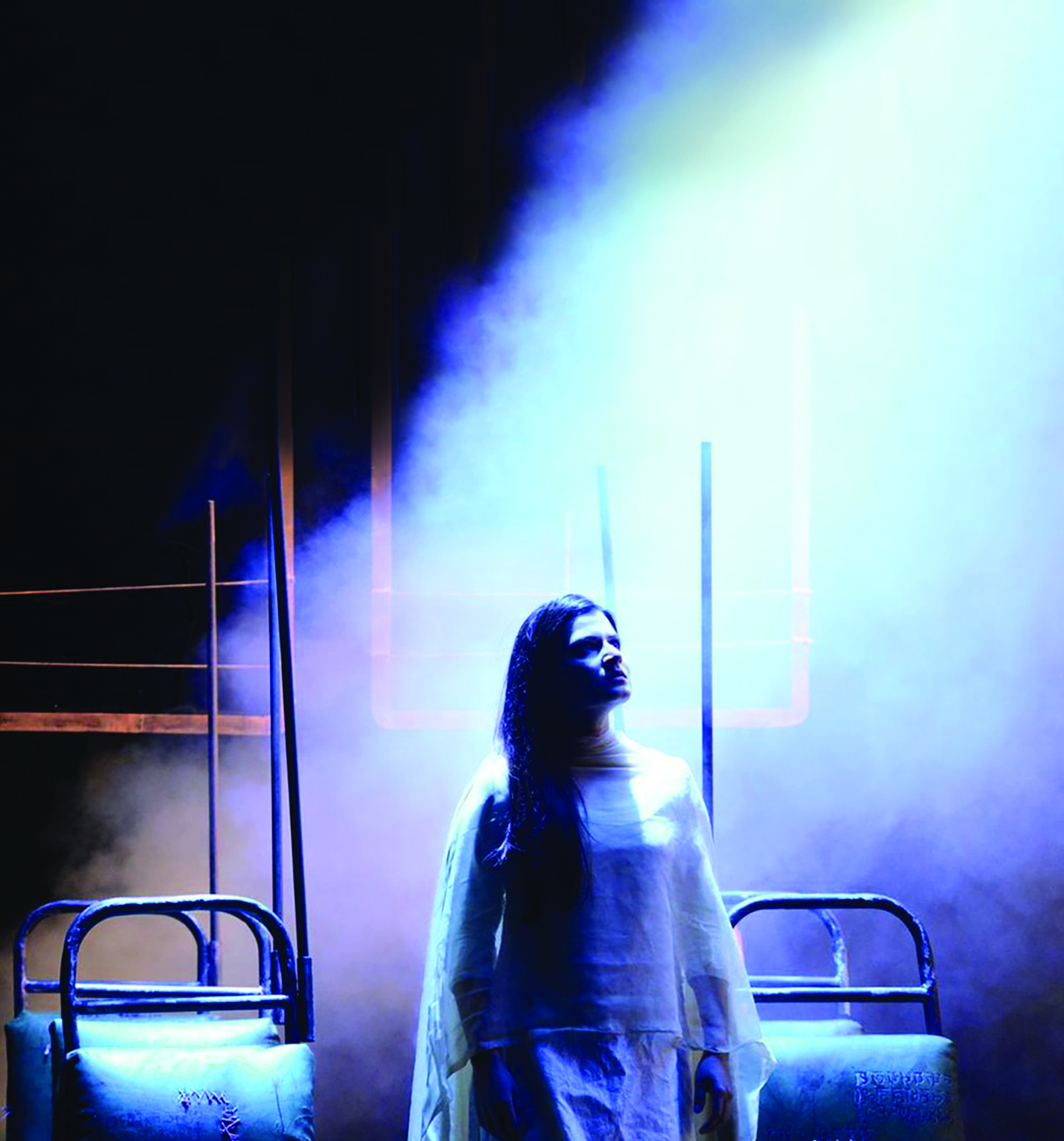 Japjit Kaur in a flowy gown in front of bus seats. Stage photo.