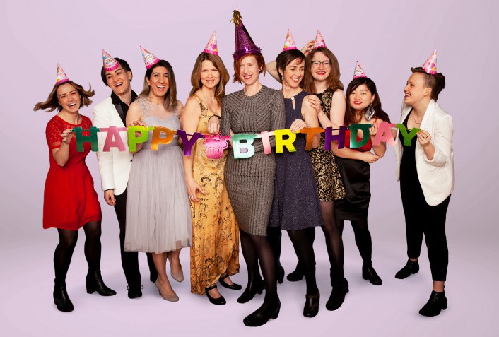 Studio photo of the Nightwood staff wearing birthday hats and holding a Happy Birthday sign.