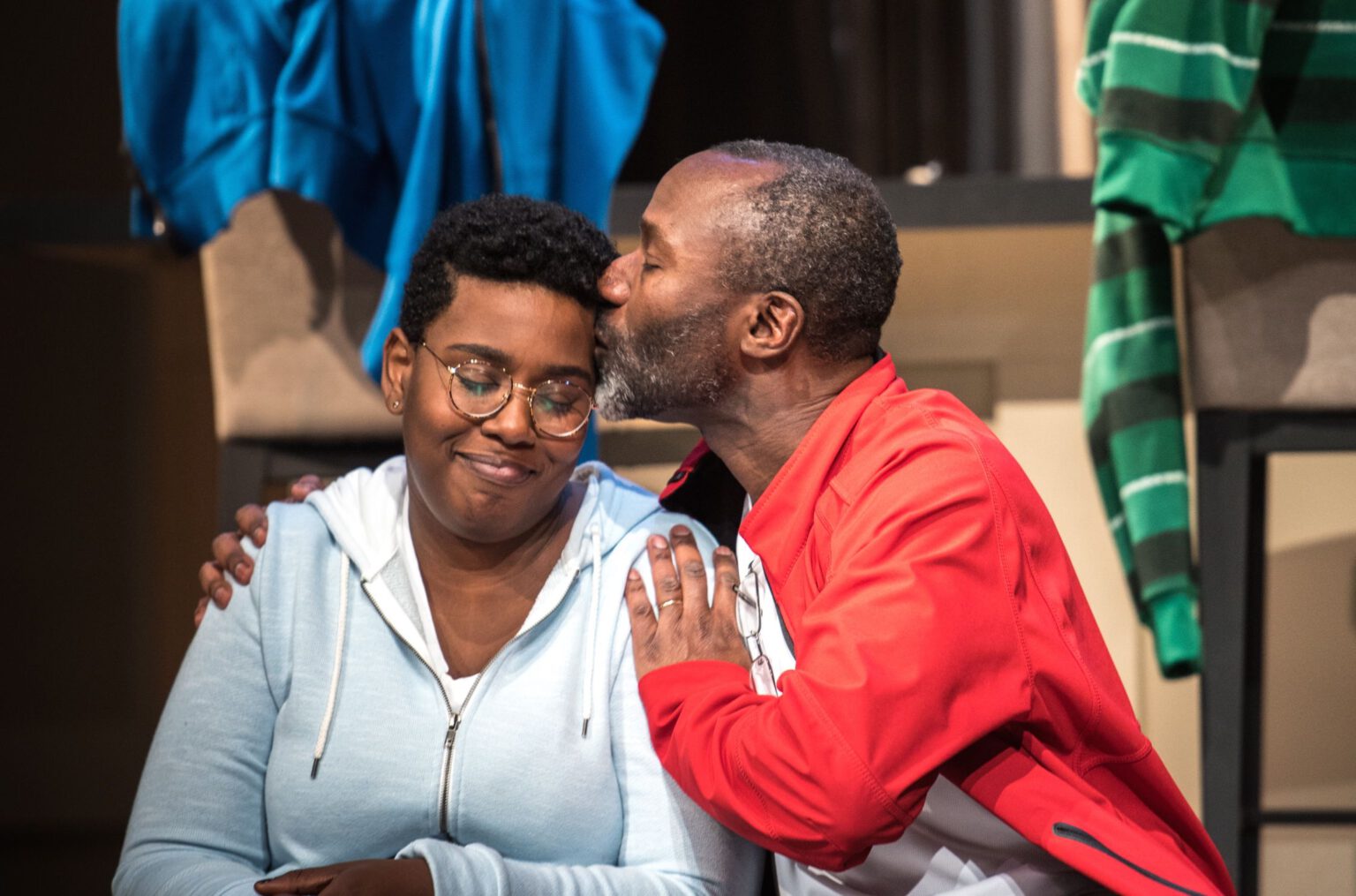 Man kissing a woman on the side of her head.