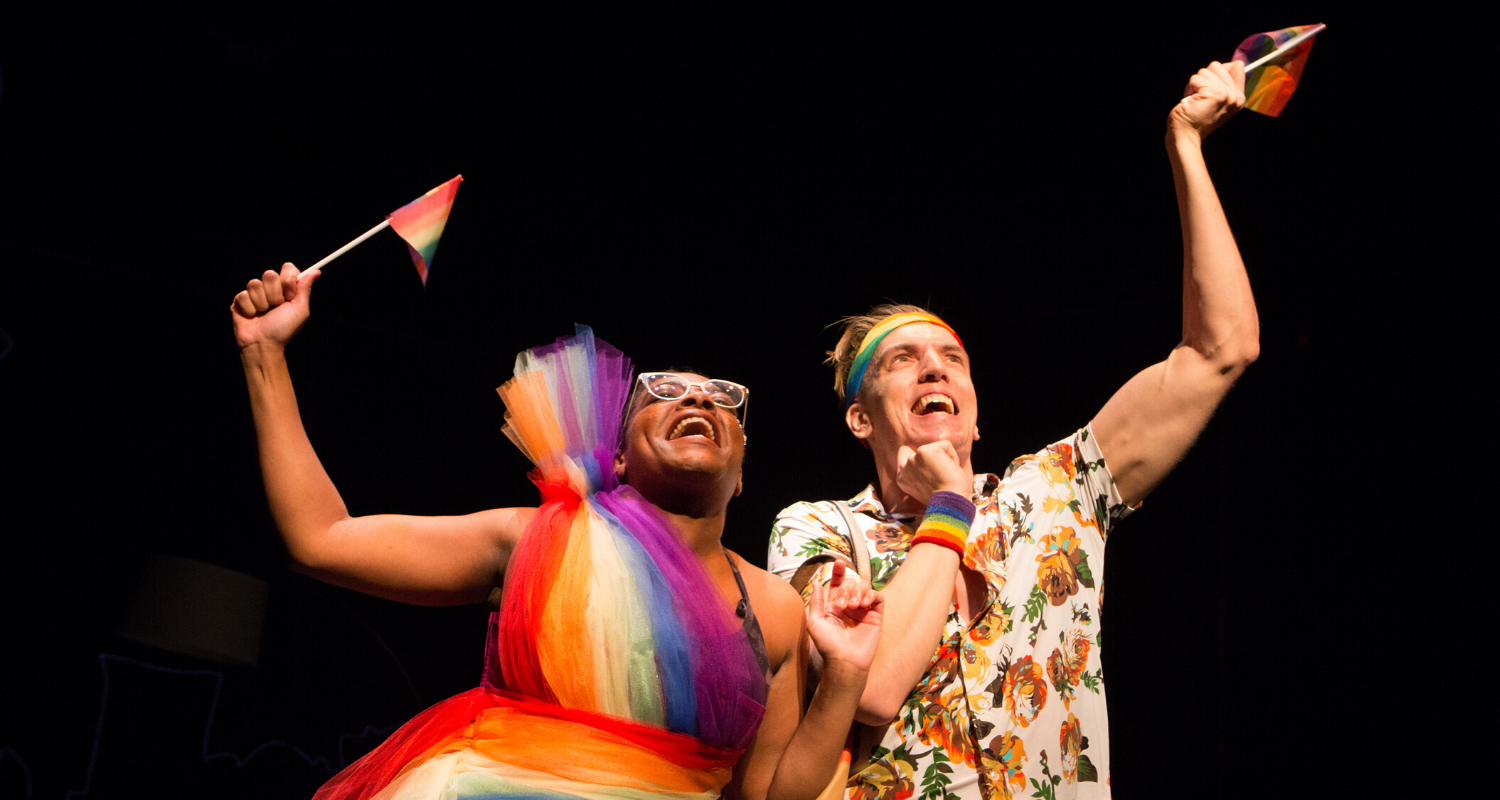 Monice Peter and Adrian Shepherd-Gawinski waving pride flags. Stage photo.