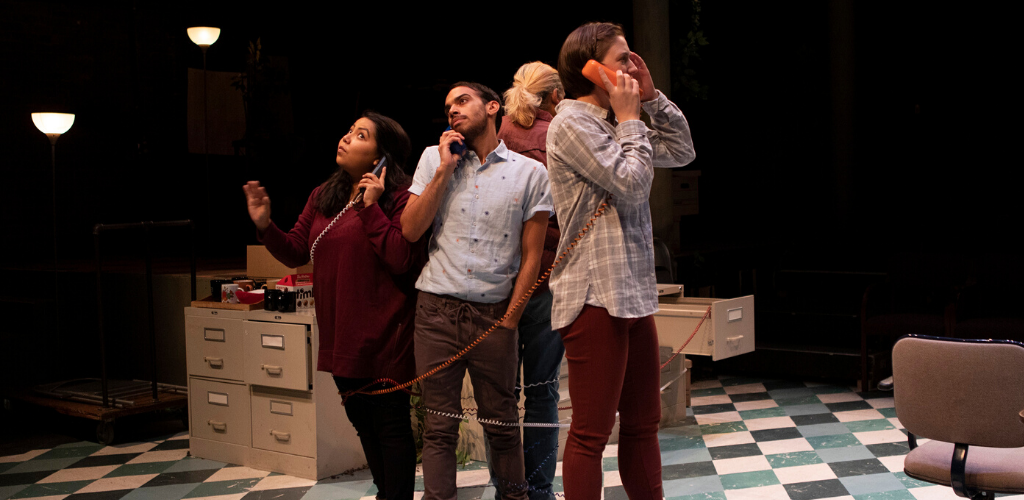 Four people stand back to back, wrapped in phone cords.