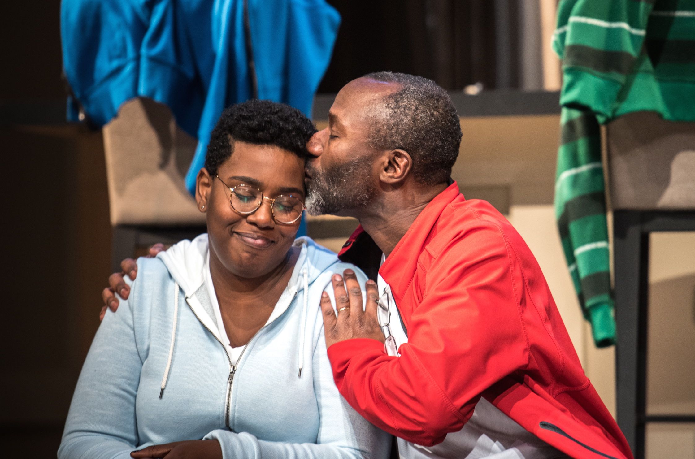 Andrew Moodie kissing Meghan Swaby on the side of her head. Stage photo.