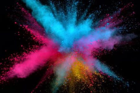 Colourful pigment explodes outwards on a black background.