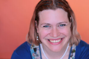 A photo of Pip Bradford, against a peach coloured background