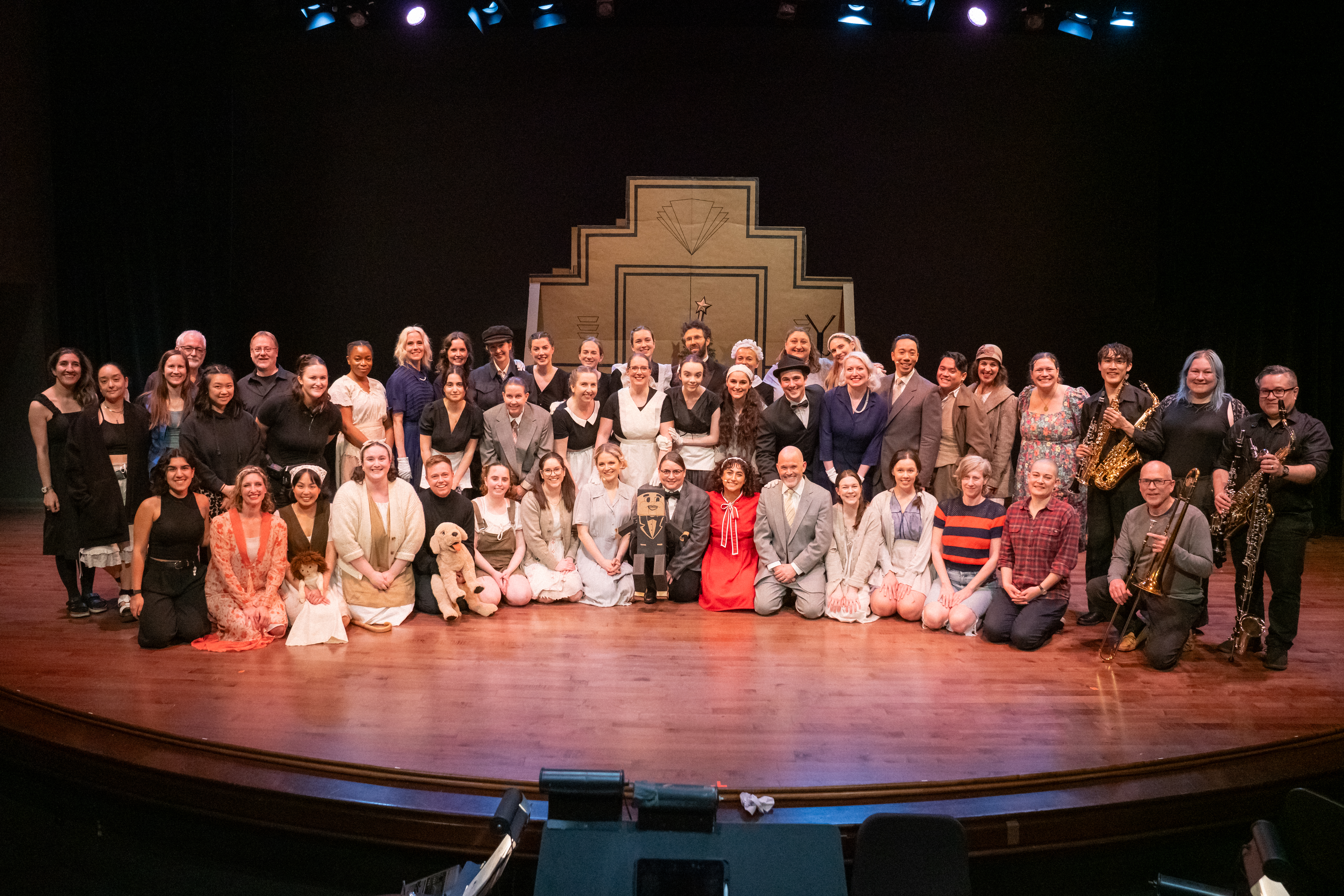The cast, band and creative team of ANNIE posed on stage