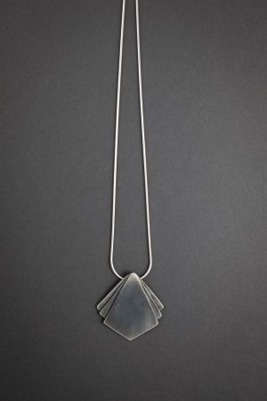 Against a grey background is a necklace that has a diamond shaped pendant at the center with two small triangle shapes on either side of the main pendant.
