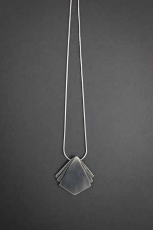 Against a grey background is a necklace that has a diamond shaped pendant at the center with two small triangle shapes on either side of the main pendant.